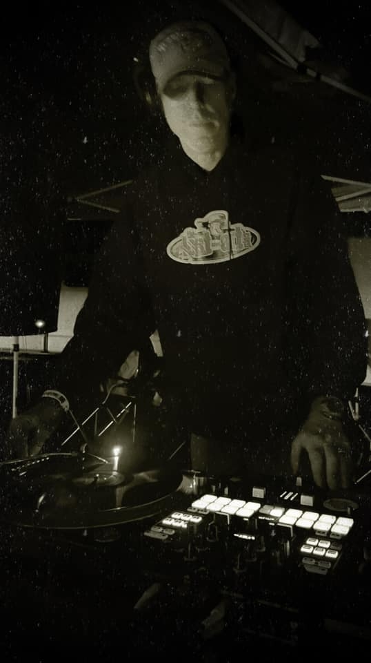 DJ Natural Nate® on the decks in black and white with rain effect, TLA logo shirt